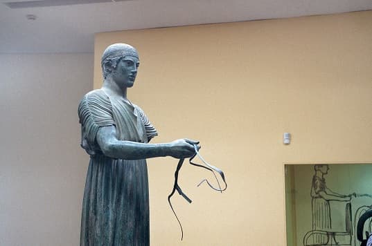 Photo of The Charioteer of Delphi statue on display at the Delphi Archaeological Museum, Greece.