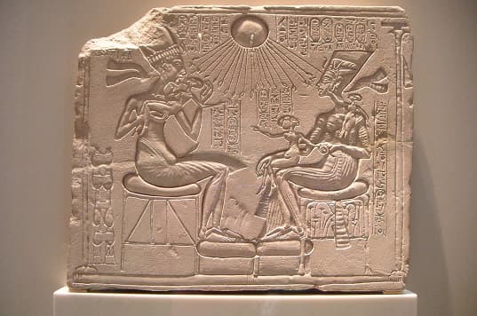 Akhenaten, Nefertiti and their three daughters sit beneath the rays of the sun god Aton, holding Ankh-symbols.