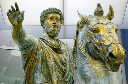 A bronze statue of Marcus Aurelius on horseback, with his arm outstretched and hand open as if addressing a crowd.