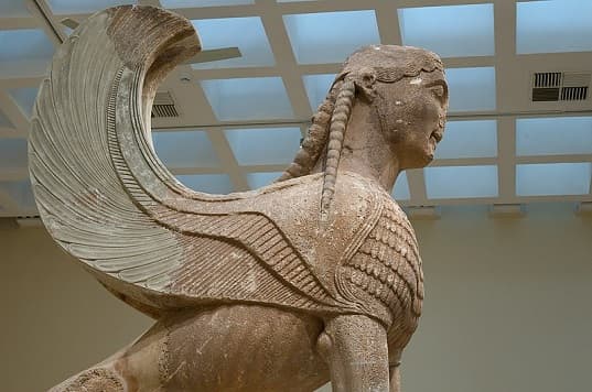 Right side view of the Sphinx of Naxos, showcasing the detailed feathers on its chest and wings and the intricate carving of the lioness body.